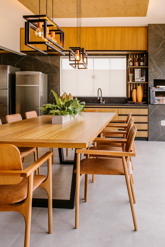 contact-img Stylish modern kitchen featuring wooden dining table with chairs, stainless steel fridge, and indoor plants.