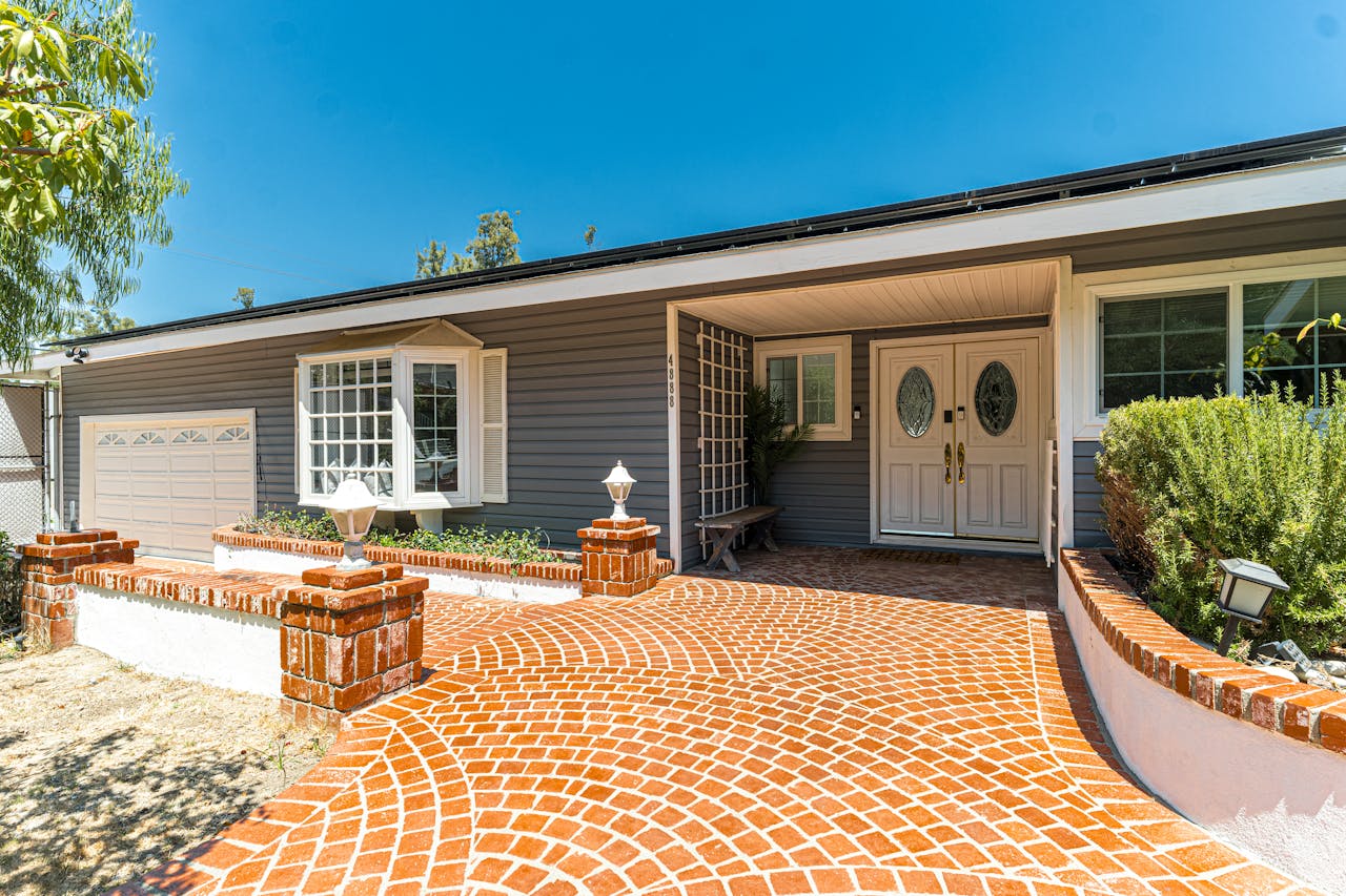 Beautiful suburban house featuring a stylish brick driveway and spacious patio.