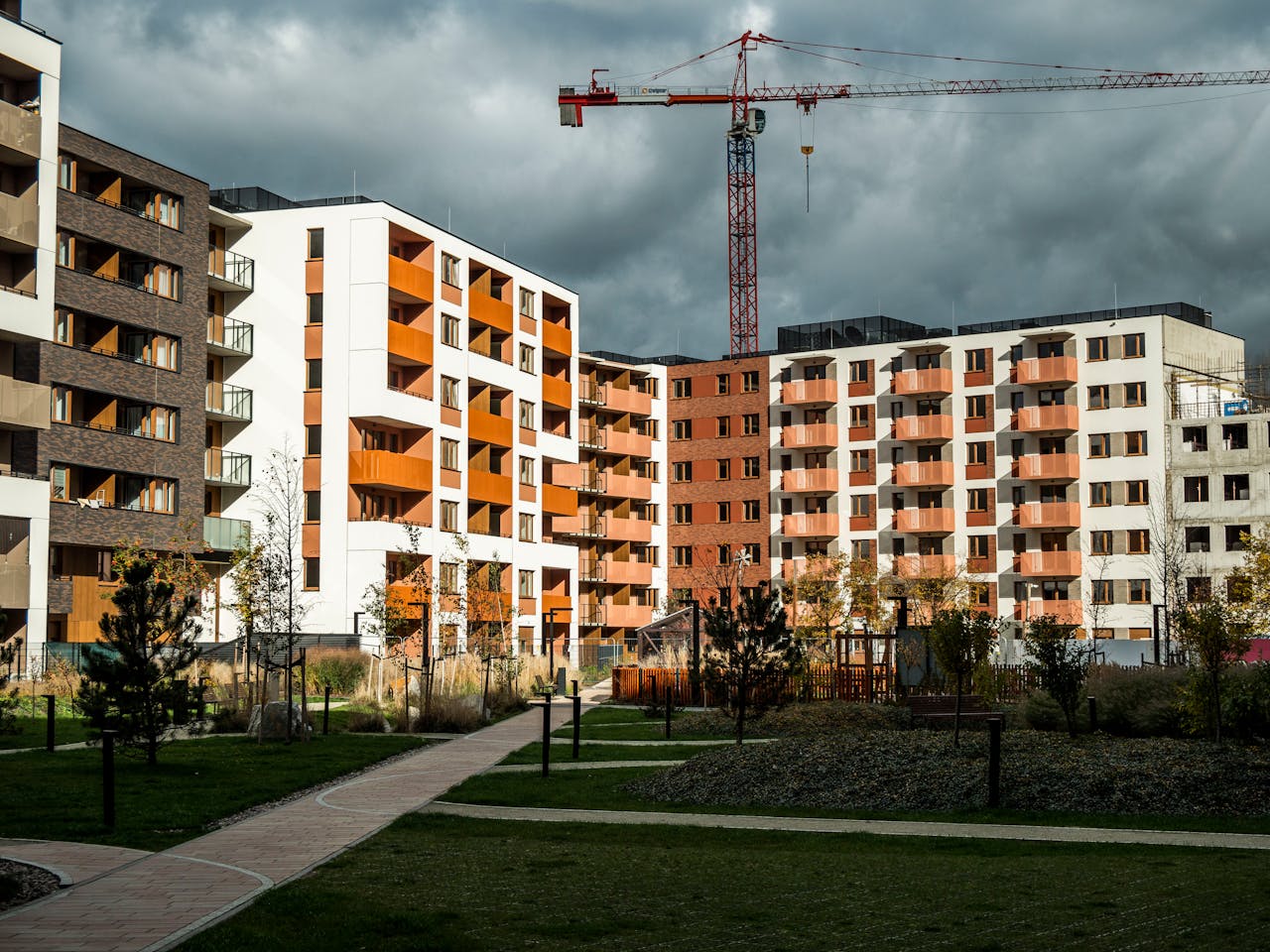 services-04 Newly built residential buildings under cloudy skies with a construction crane.