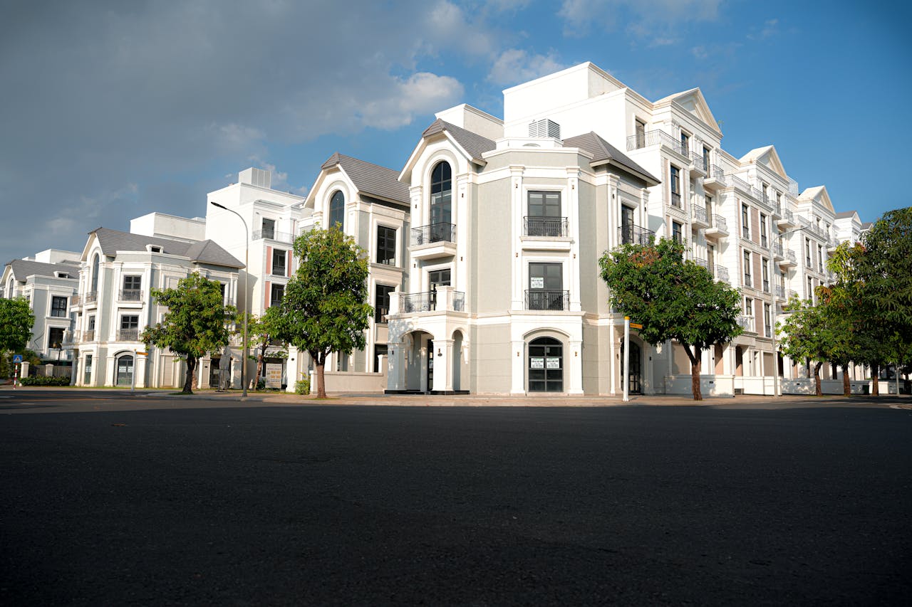 about-img A modern apartment complex with classic architectural design under a bright blue sky.