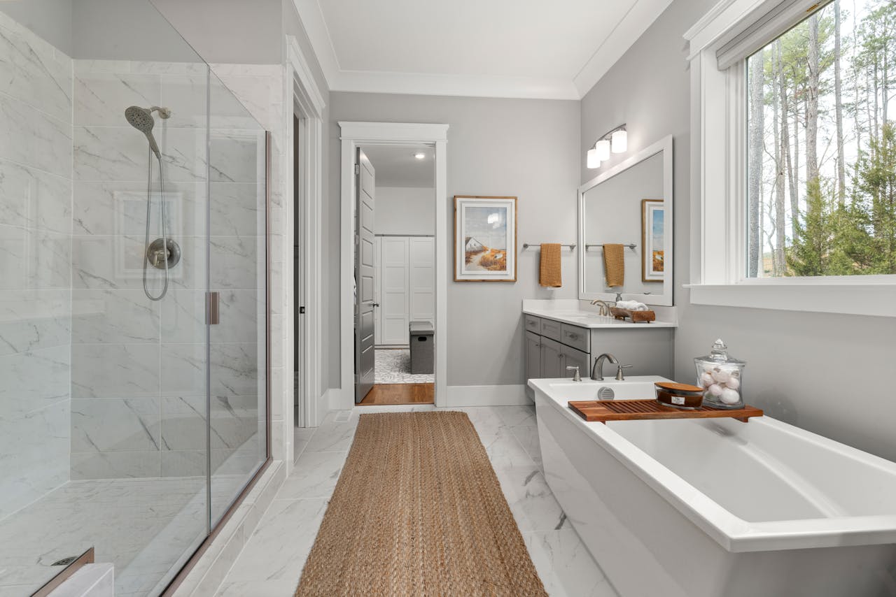 services-01 Elegant bathroom with a freestanding bathtub, glass shower, and large window view.