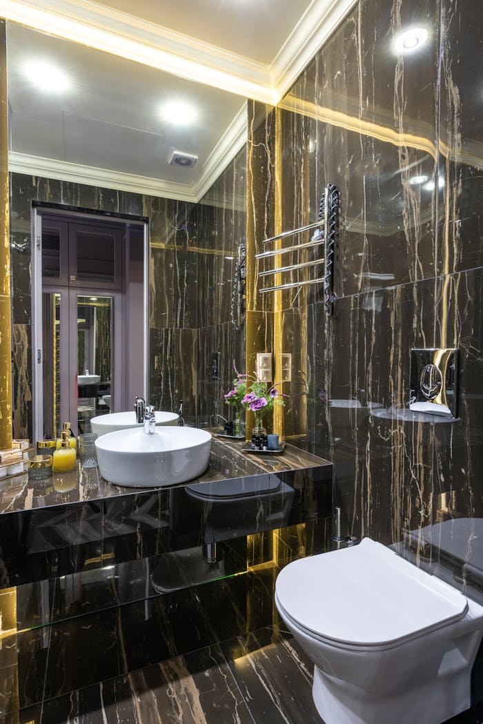 services-img Contemporary bathroom with toilet bowl and washbasin reflecting in mirror under glowing lights in house